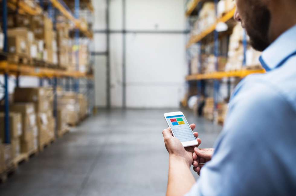 man with mobile device in fulfillment warehouse